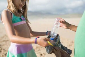 young girl at the beach cleaning up trash