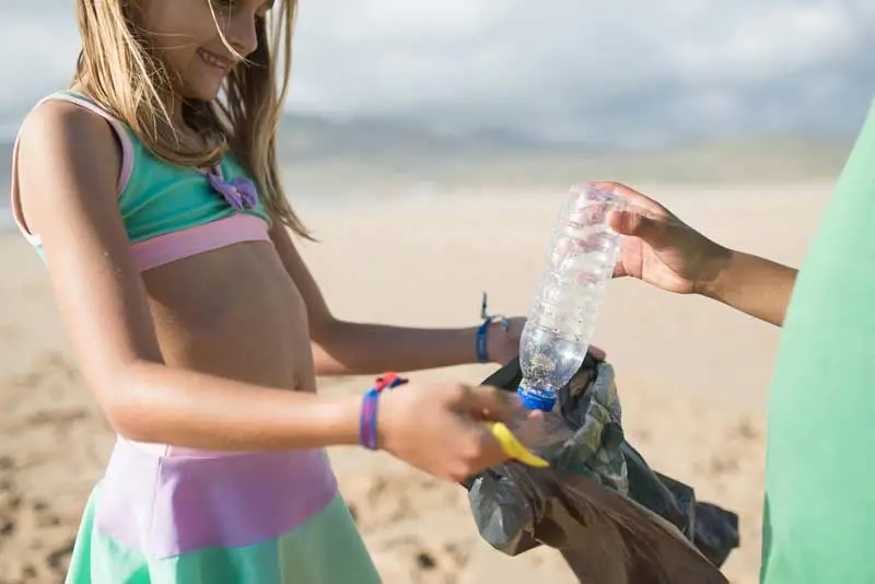 young girl at the beach cleaning up trash