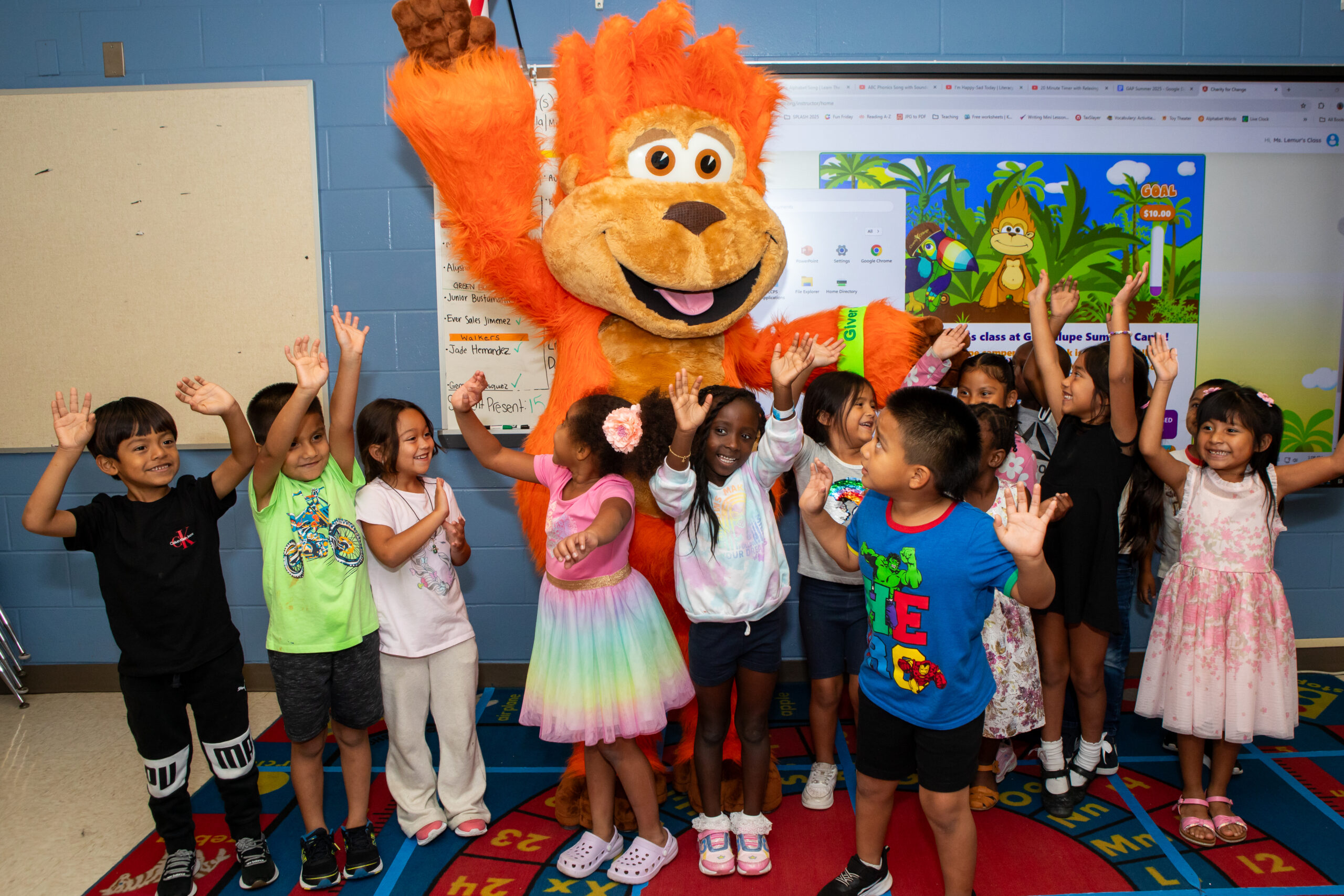 Kindergartners through 2nd graders posing with Giver with Charity for Change program in background